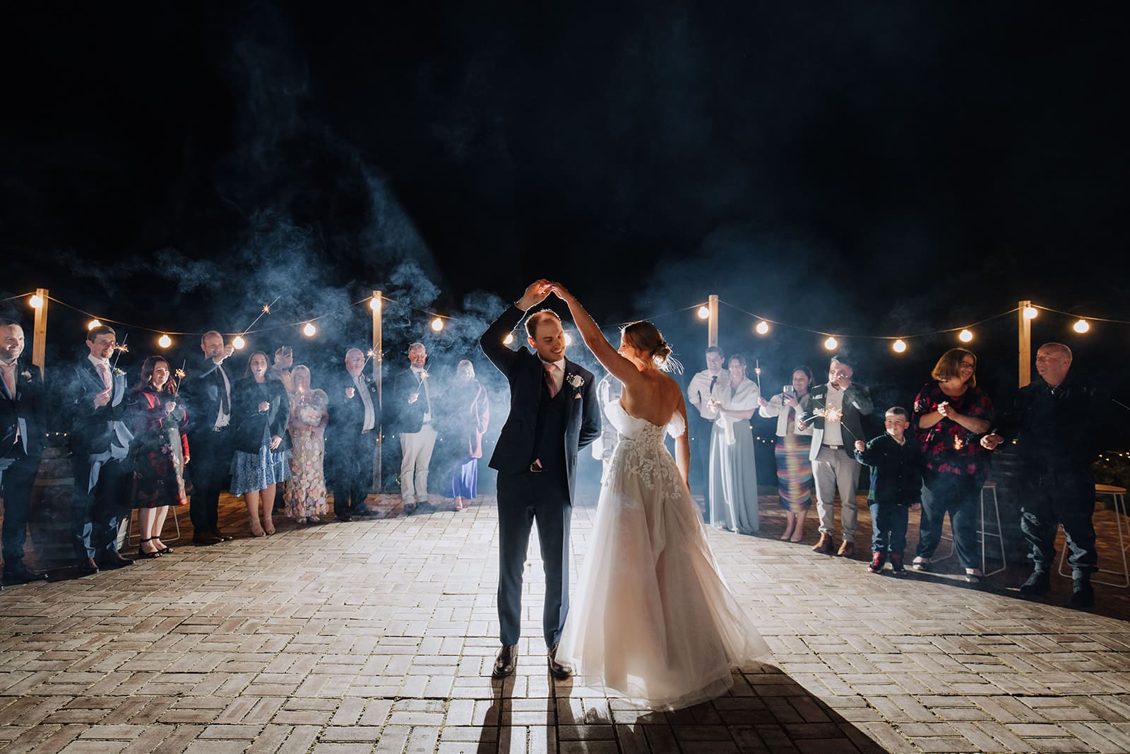 Aleisha and Mitchell sharing their first dance outside the marquee as guests wave sparklers at Growwild Wildflower Farm.