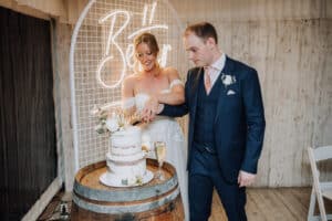 Aleisha and Mitchell cutting their semi-naked wedding cake at Growwild Wildflower Farm.