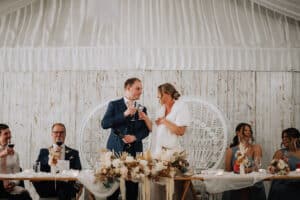 Bride Aleisha and groom Mitchell toasting champagne at the sweetheart table during their wedding reception speeches.