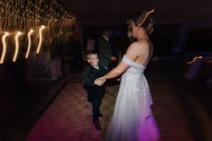 Bride Aleisha dancing hand in hand with a young wedding guest on the reception dancefloor at Growwild.