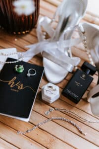 Staged flat lay of Cathy and Nick's wedding day details, including their wedding rings, handwritten vow books, and bridal shoes before the ceremony.